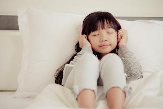 Image of child with headphones sitting on a couch